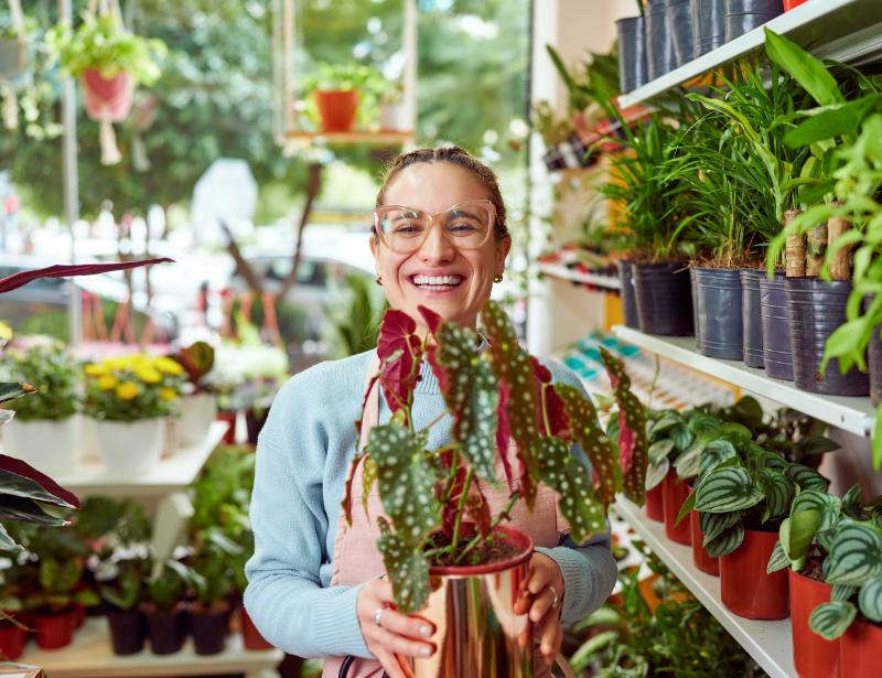 Woman business owner smiling holding plants - Community Futures Ontario
